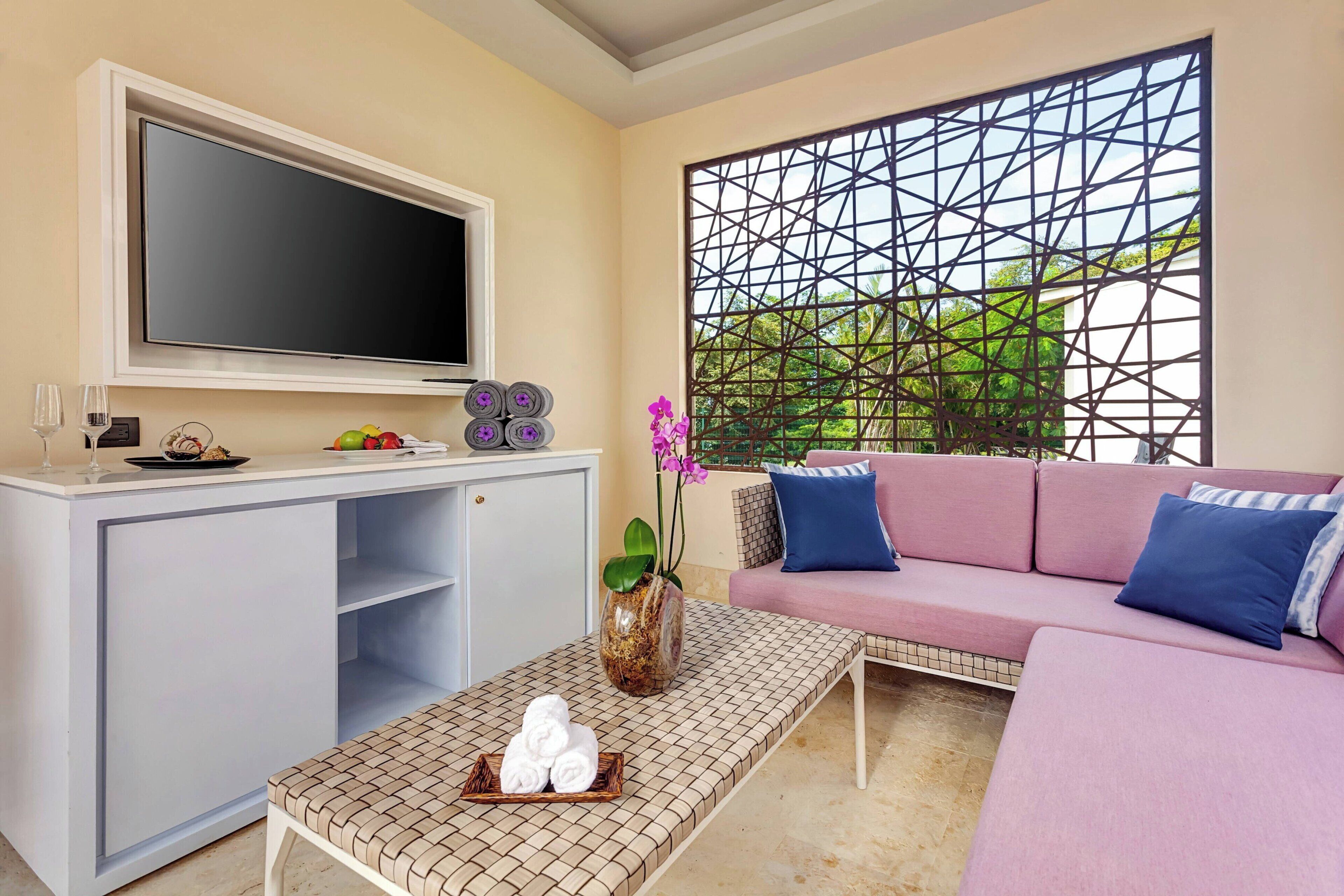 Ein Wohnzimmer mit Fernseher, Sofa, Couchtisch und einer dekorativen Wandverkleidung.