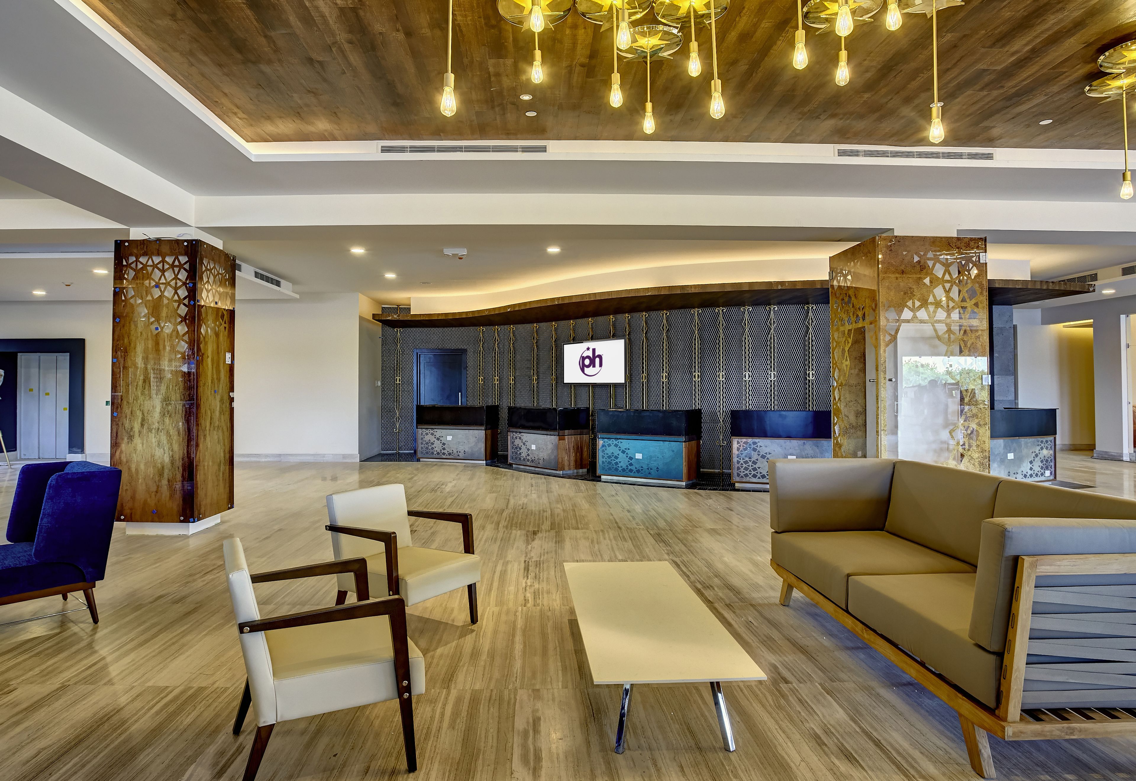 A spacious lobby with a wooden ceiling, modern furniture, and a reception area with a logo.
