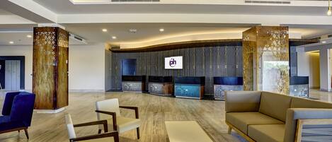 A spacious lobby with a wooden ceiling, modern furniture, and a reception area with a logo.