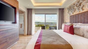 A modern hotel room with a large bed, a flat-screen TV, a balcony with a scenic view, and a decorative wall.