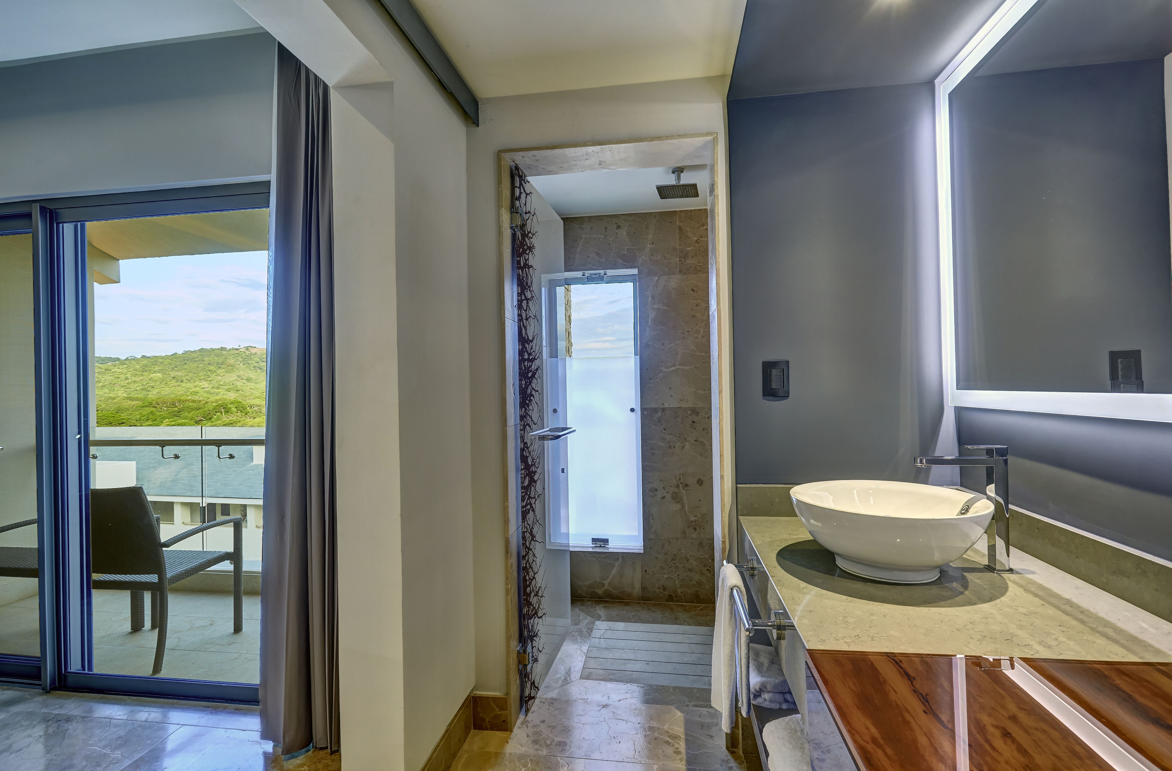 A modern bathroom with a large mirror, a white sink, and a shower area.