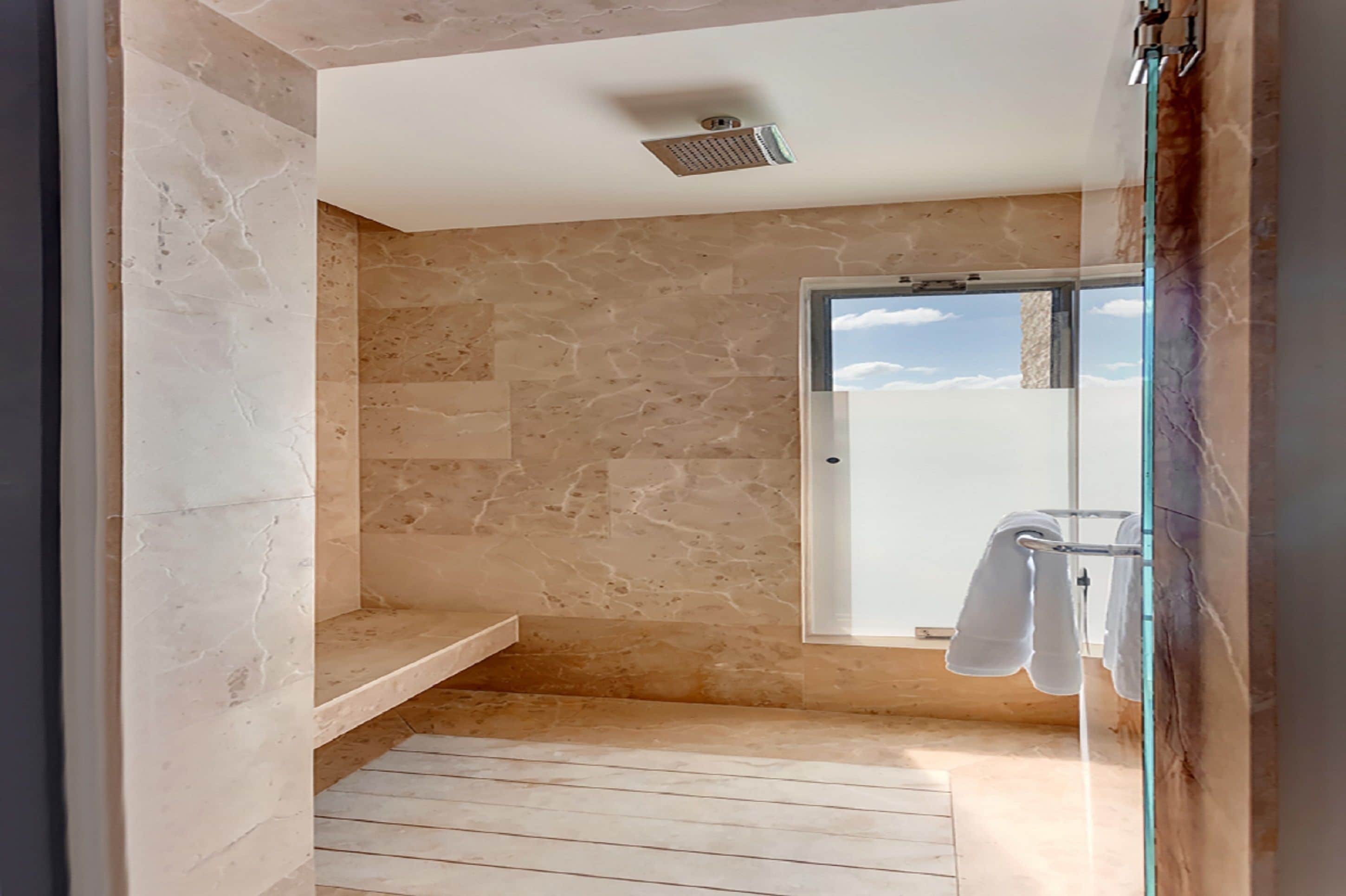 A modern bathroom with a stone wall, a glass shower enclosure, and a towel rack.