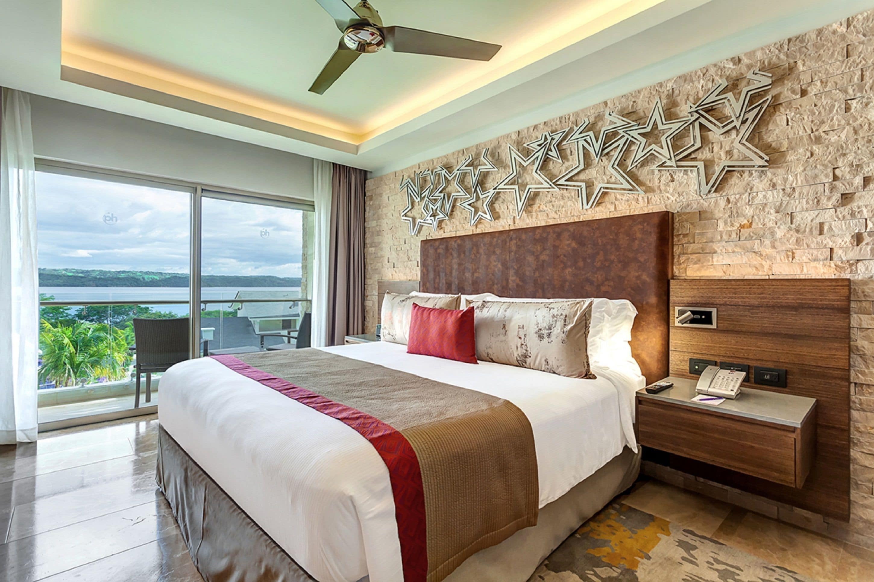 A spacious bedroom with a large bed, a nightstand, and a view of the outdoors.