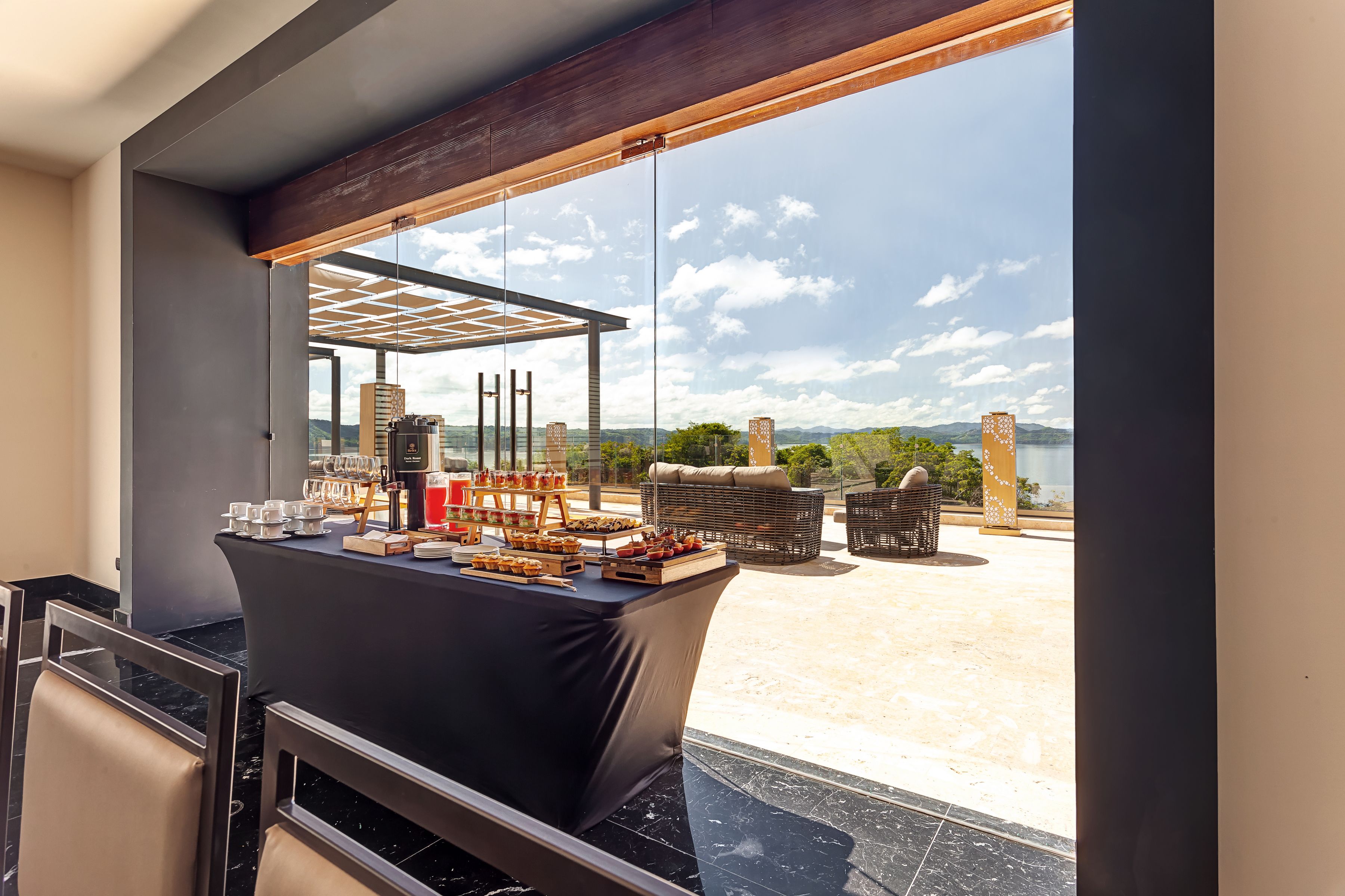 A dining area with a table set for a meal, overlooking a scenic view of mountains and a body of water.