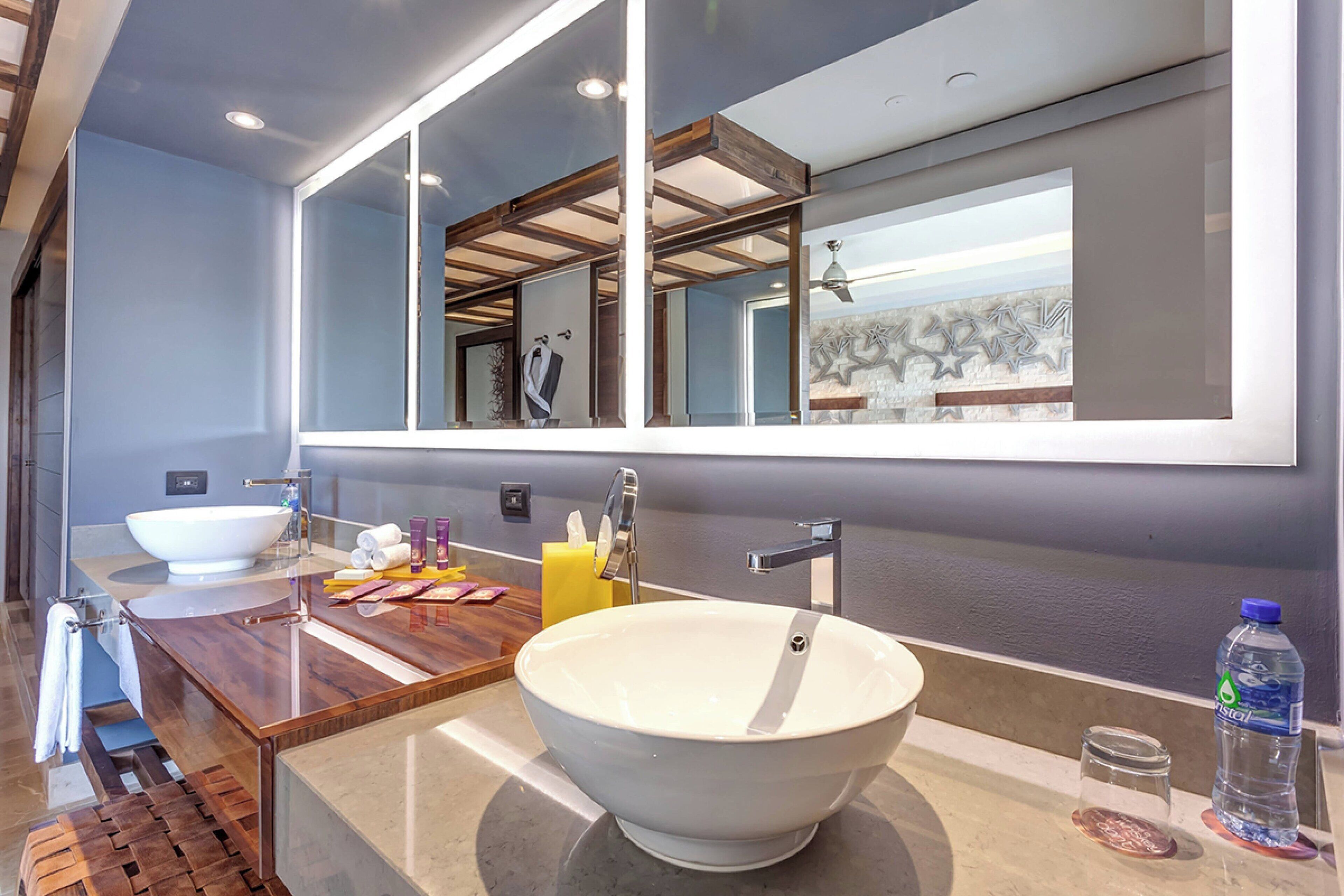 Un baño moderno con un espejo grande, un mueble de tocador de madera, un lavabo blanco y un perchero para toallas.