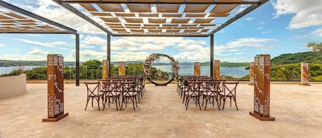 Decoração de casamento ao ar livre com pérgola, cadeiras e arco de flores.