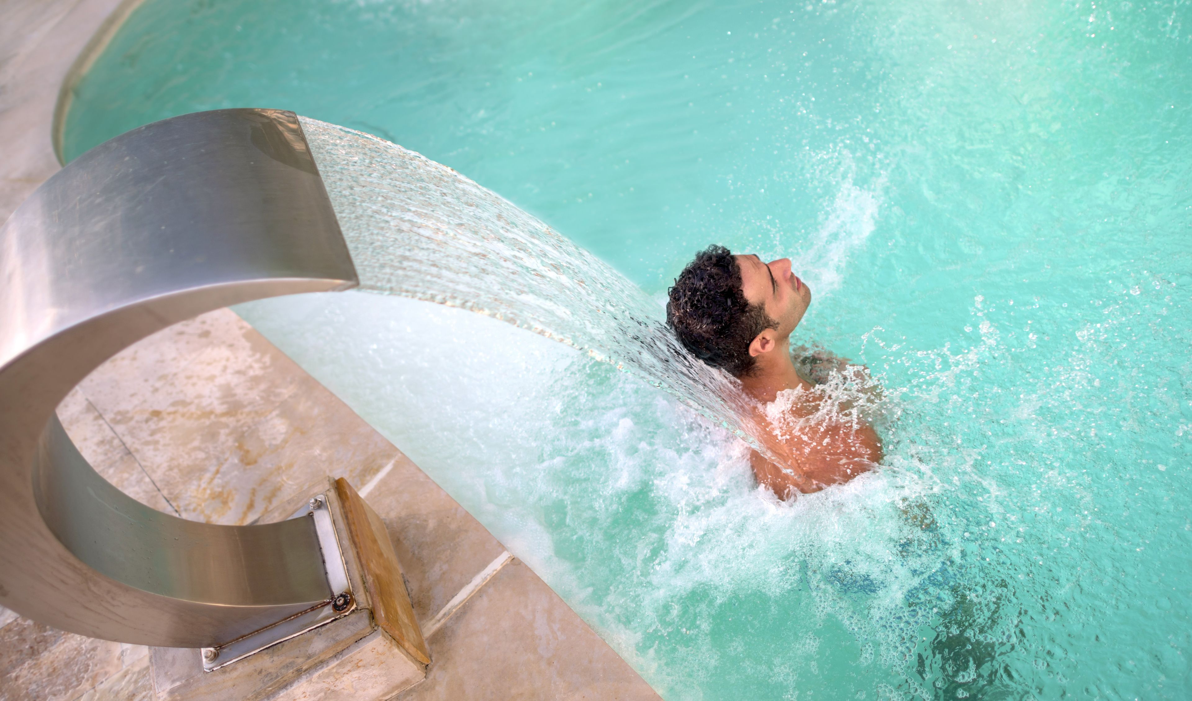 A person in a pool with a water slide.