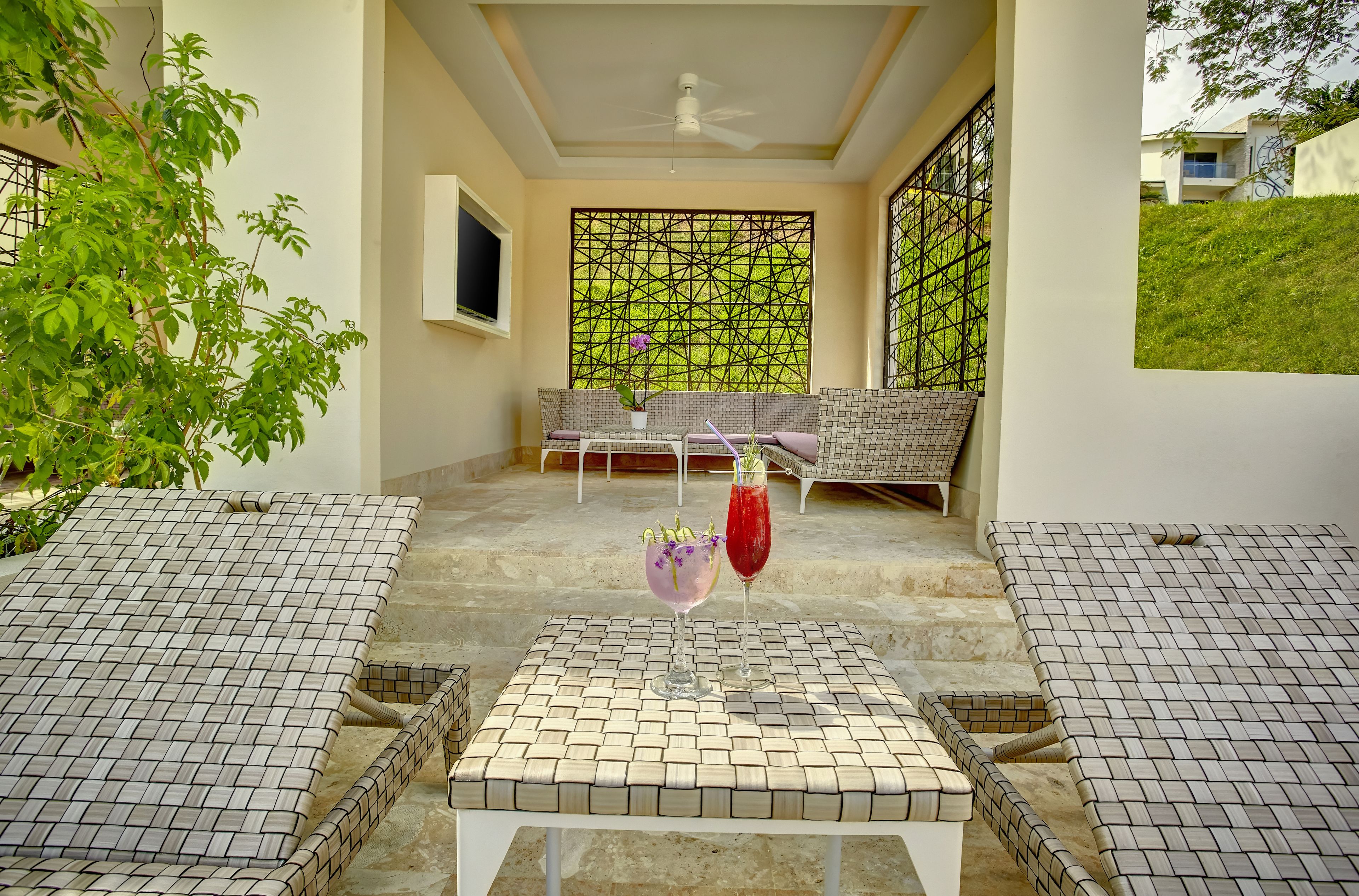 A sunlit patio with a table and chairs, a decorative screen, and a view of a hillside.