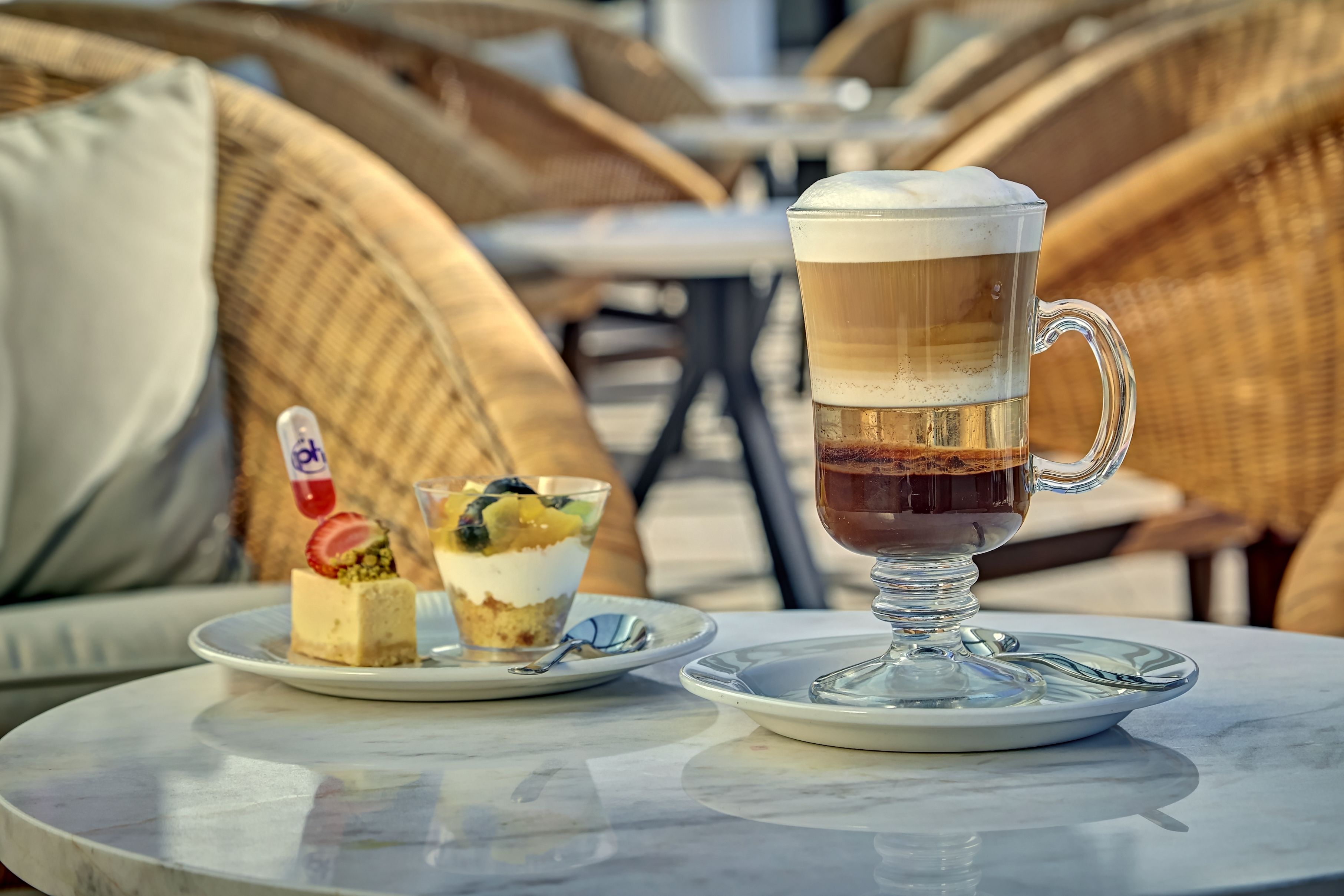 A table with a layered beverage and a dessert on a white plate.