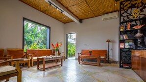 A spacious room with a large window, wooden furniture, and a decorative bookshelf. - Hoi An Corn Riverside Villa (Da Nang)