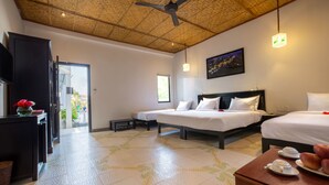 A hotel room with two beds, a ceiling fan, a wooden ceiling, a dining table with breakfast items, and a view of the outdoors. - Hoi An Corn Riverside Villa (Da Nang)