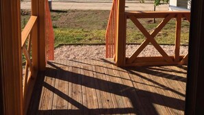A wooden deck with a view of a hilly landscape, a road, and a parked RV. - Coimbra Camping & Bungalows (Coimbra)