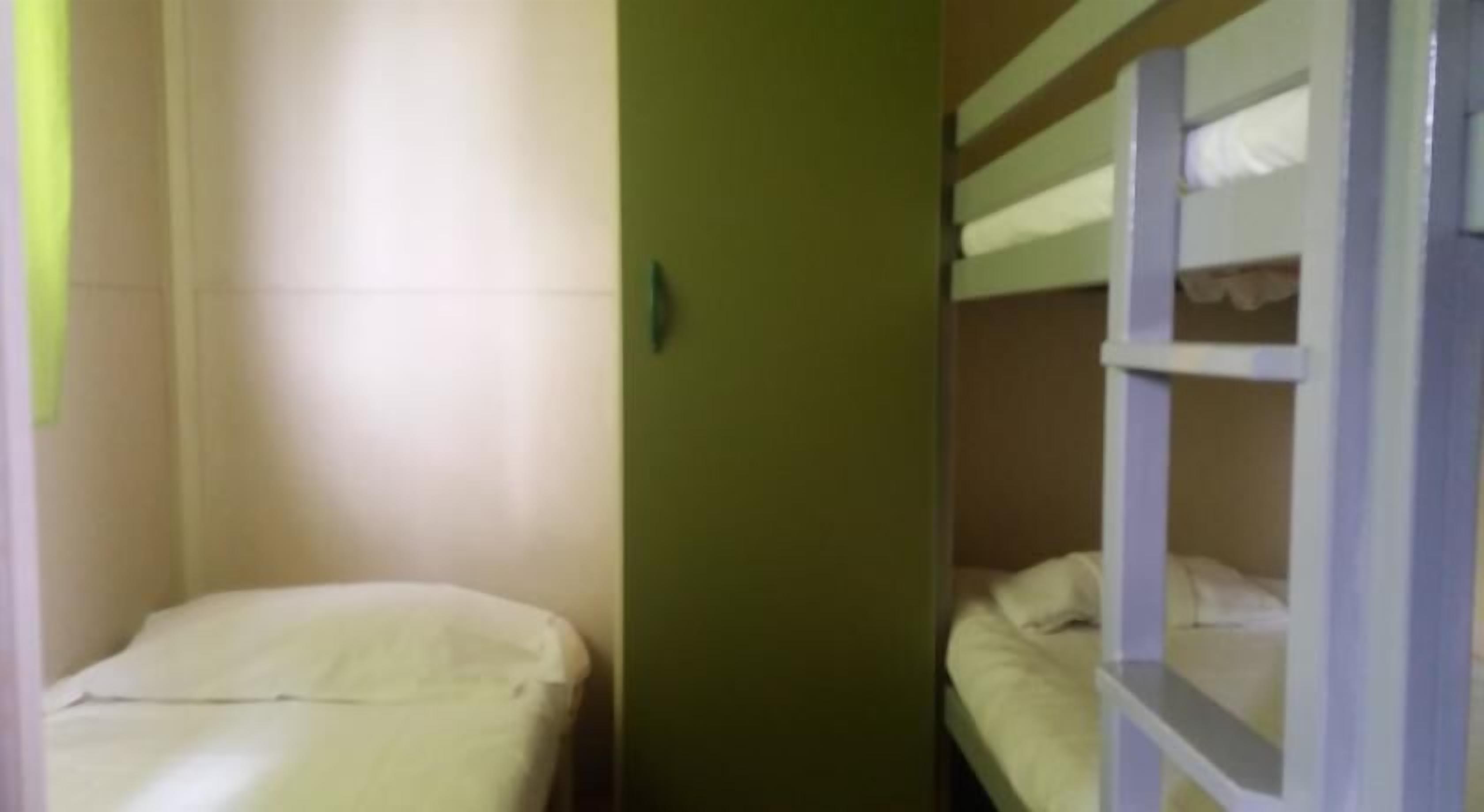 Una habitación pequeña y estrecha con literas y una cama individual.