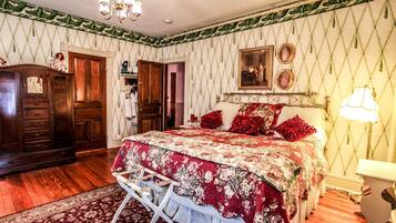 A bedroom with a large bed, wooden wardrobe, and a chandelier.