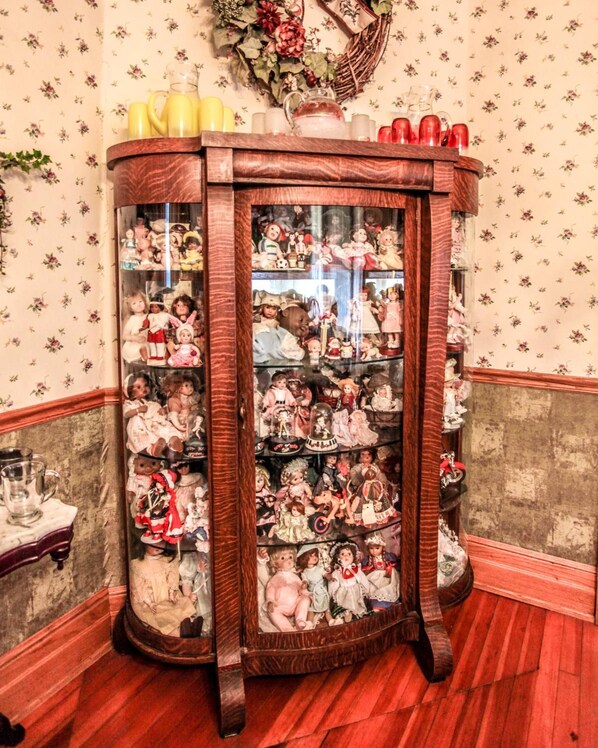 Un aparador de madera con varias repisas llenas de muñecas y figuritas.