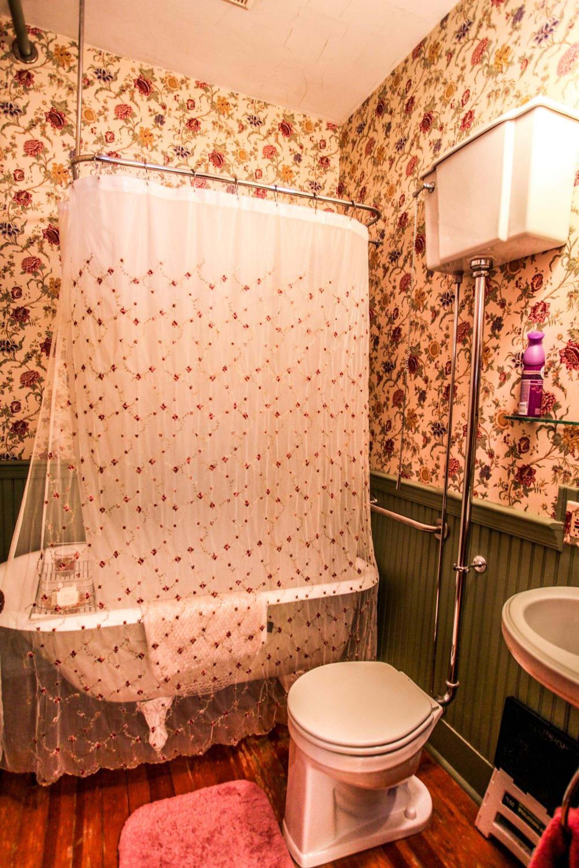 A bathroom with a shower curtain, toilet, and a shelf with toiletries.