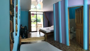 A bedroom with a bed, a desk, and a chair. There is a sliding glass door leading to a balcony.