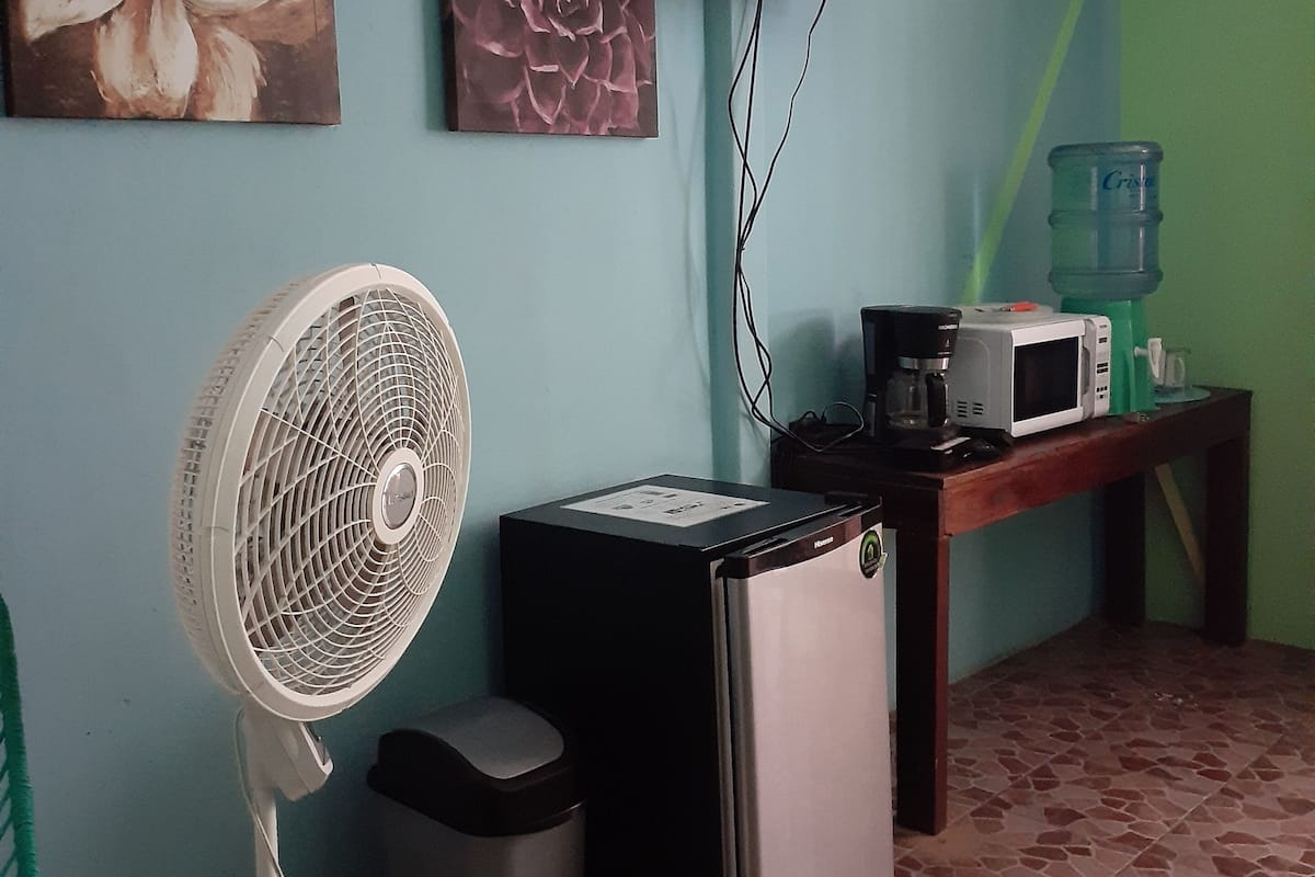 A small kitchenette with a refrigerator, microwave, and a water dispenser on a table.