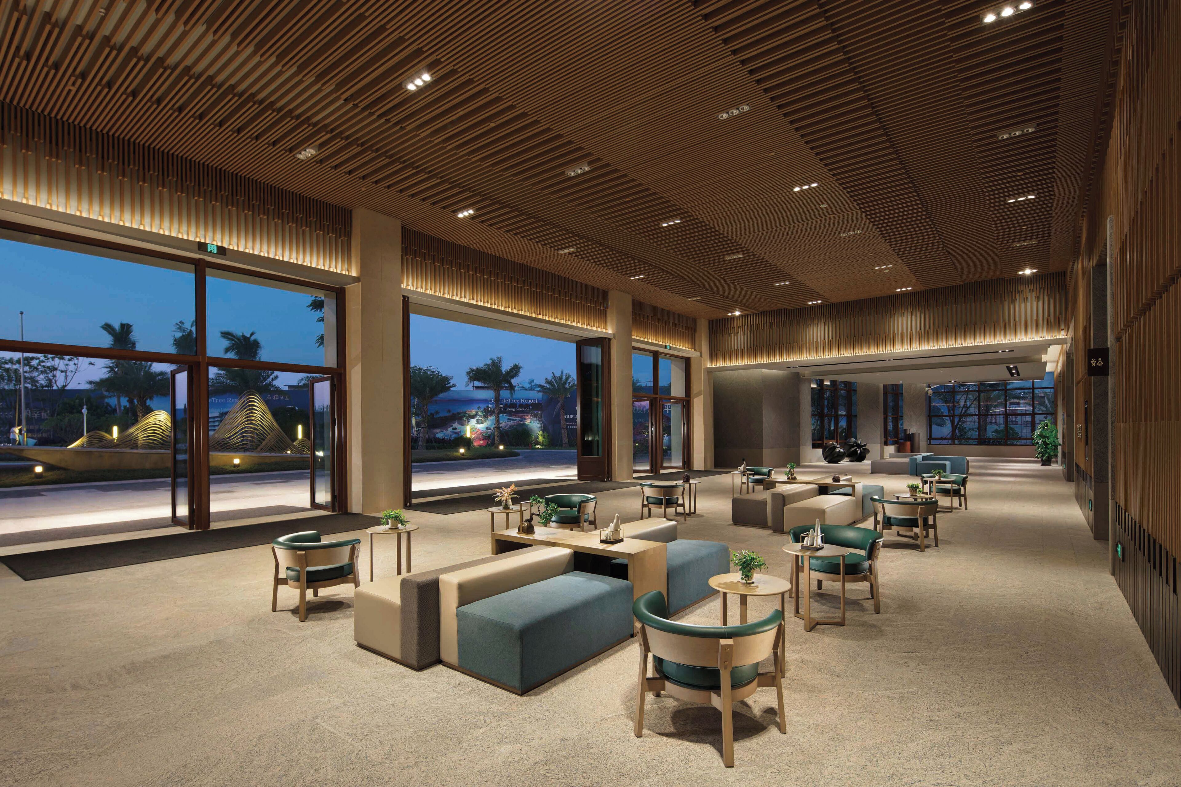 Een ruime lobby met een modern design, met een grote zithoek, een receptiebalie en grote ramen met uitzicht op buiten.