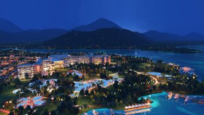 Un complejo turístico con varias piscinas, un puerto deportivo y montañas al fondo.