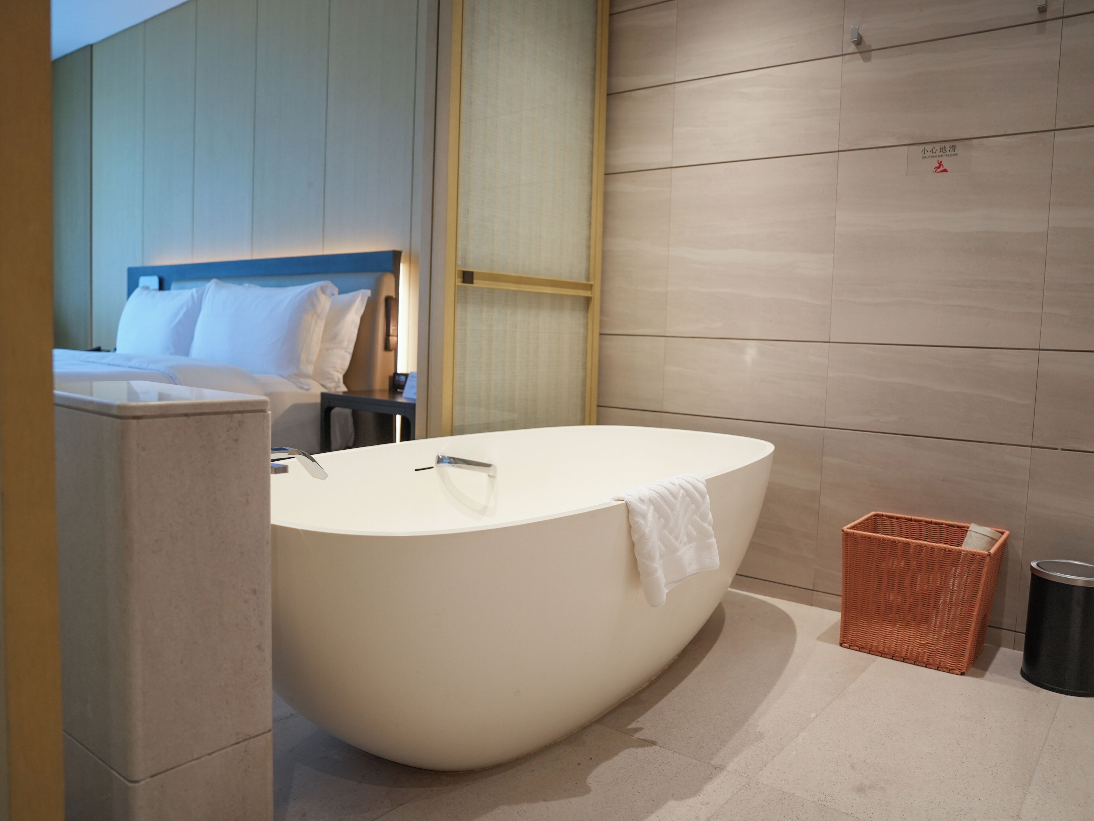 Une salle de bain moderne avec une baignoire sur pieds, un petit panier en osier et une poubelle.