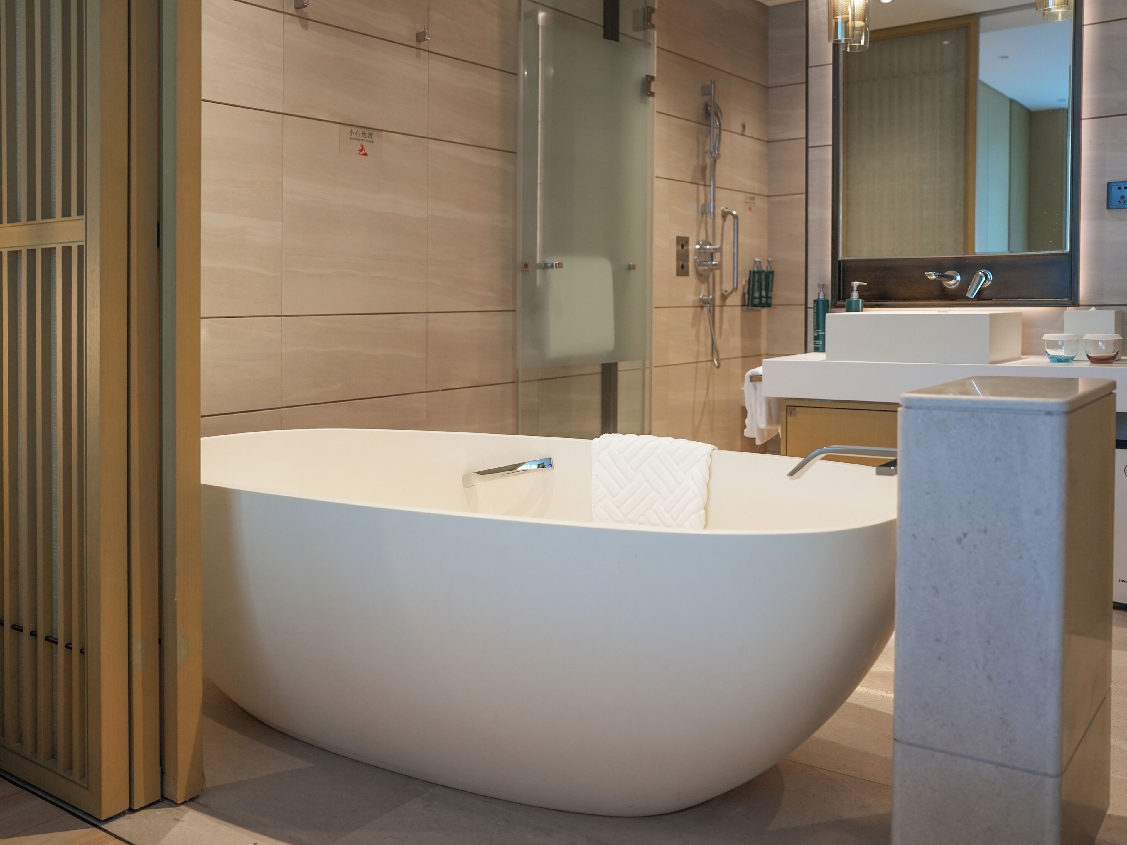 A modern bathroom with a freestanding bathtub, a glass shower enclosure, and a large mirror above the sink.