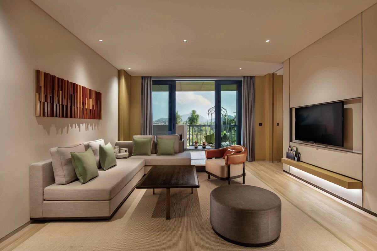 A modern living room with a sofa, coffee table, ottoman, and a TV mounted on the wall.