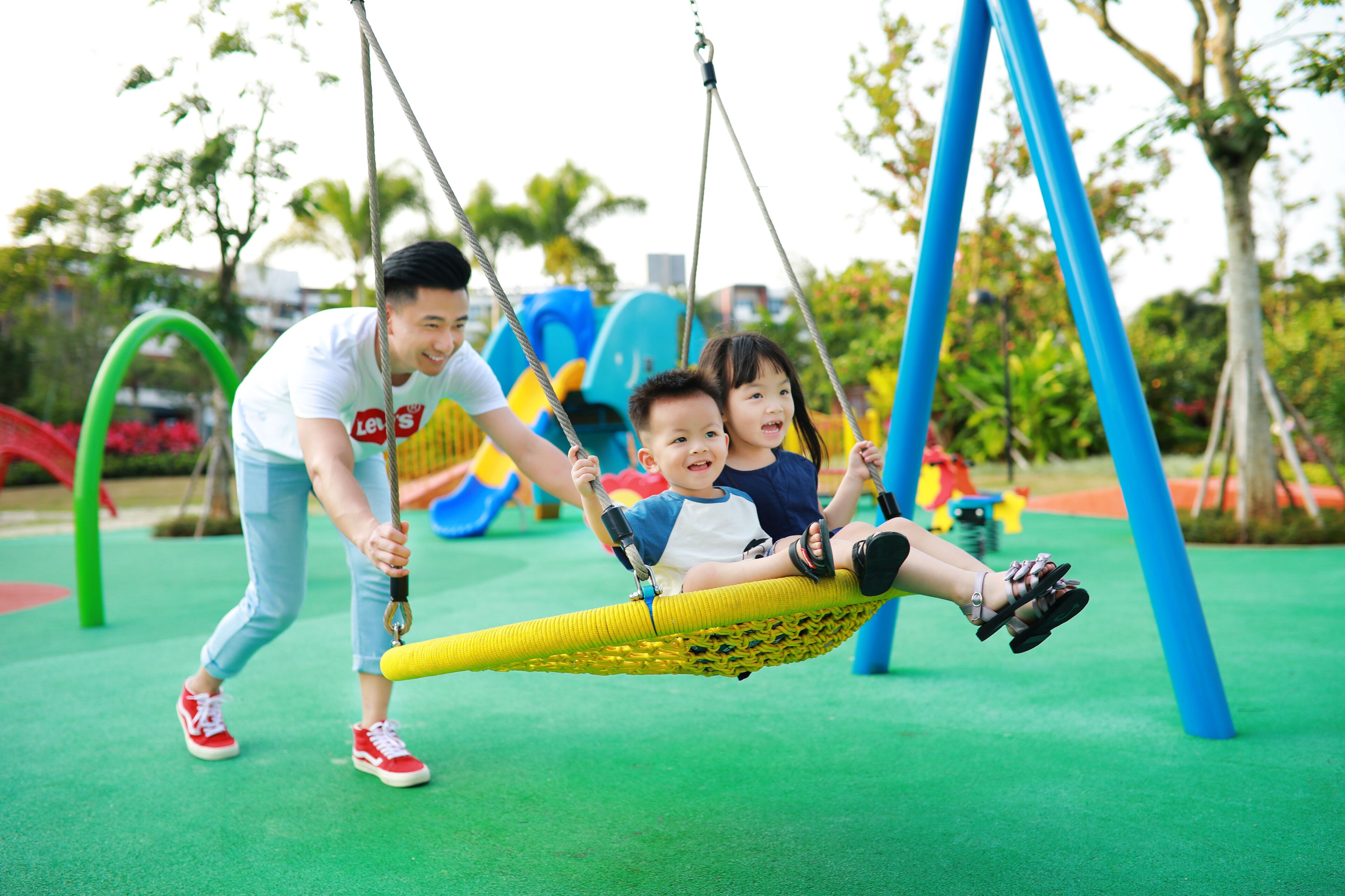 A swing set in a playground with a green rubber surface.