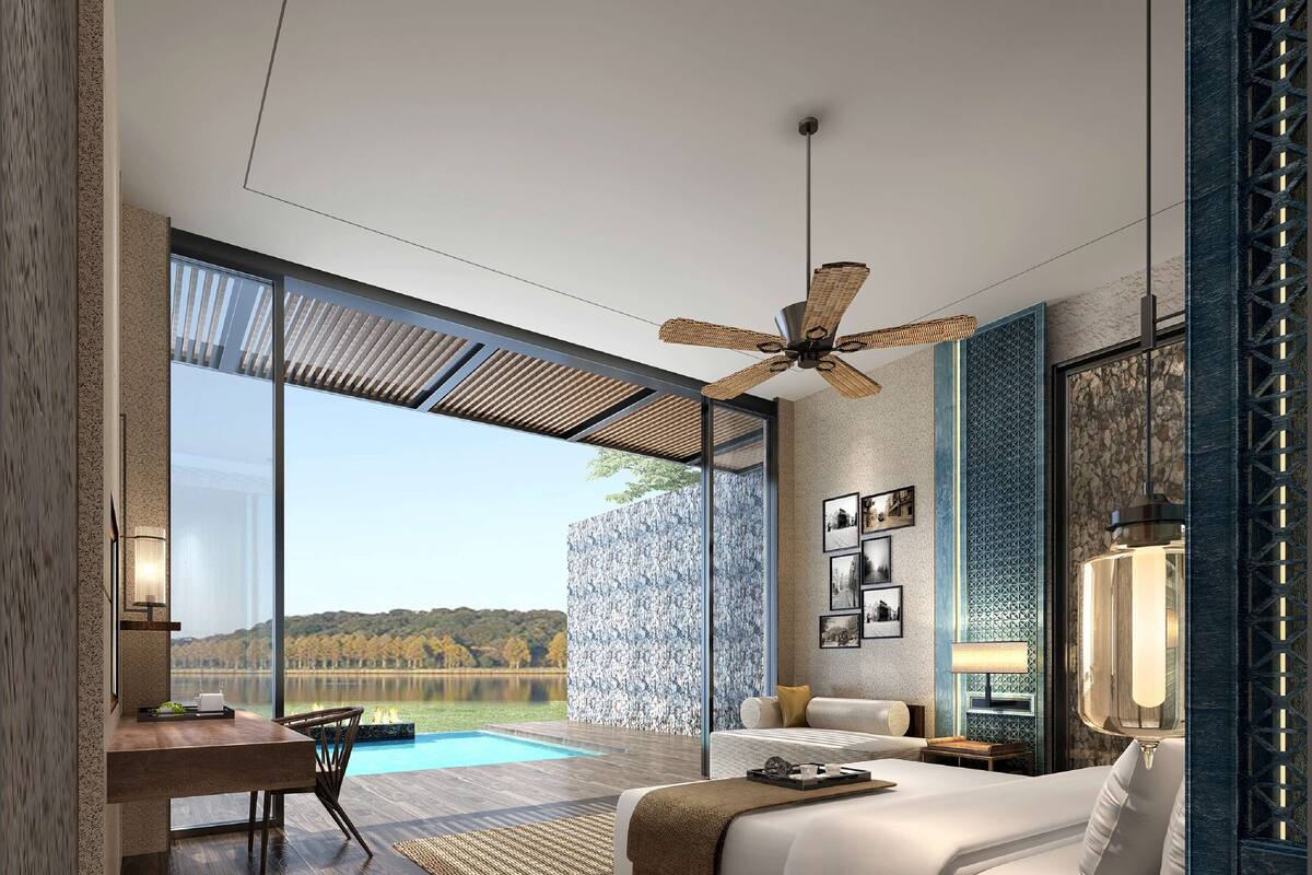 A modern hotel room with a large bed, a desk, and a view of a lake.