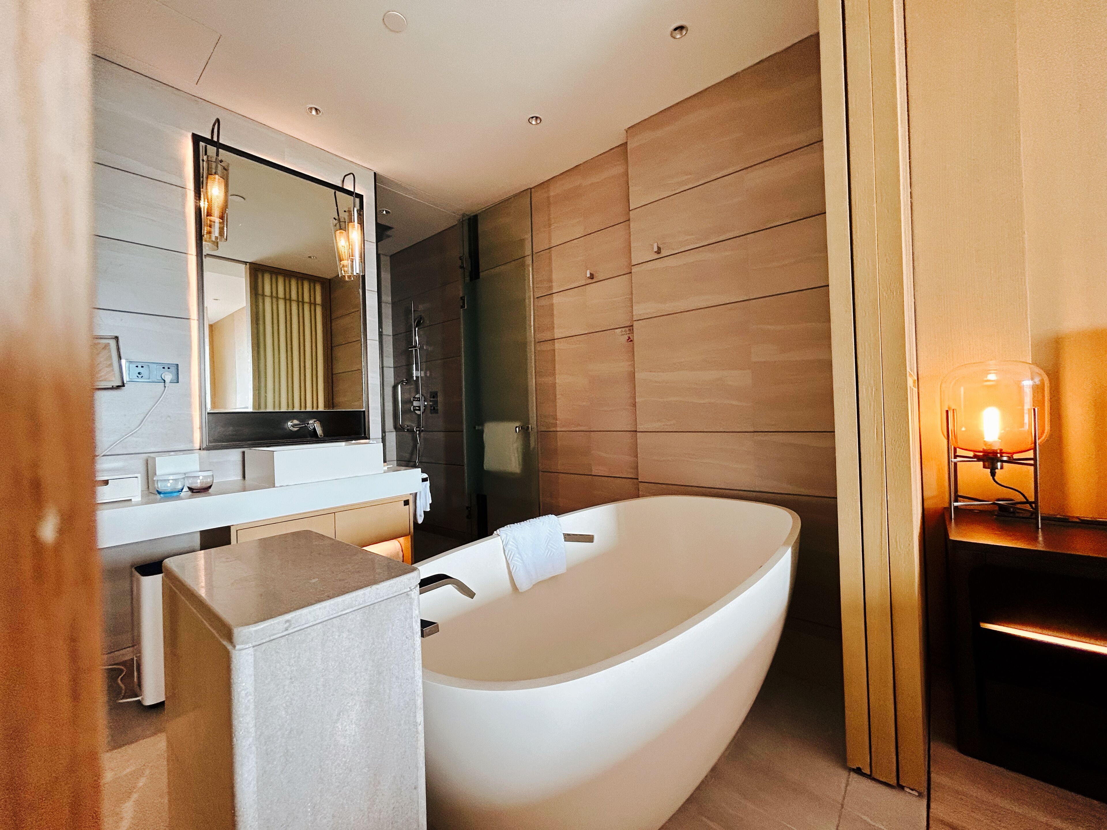 A modern bathroom with a freestanding bathtub, a vanity with a mirror, and a shower area.