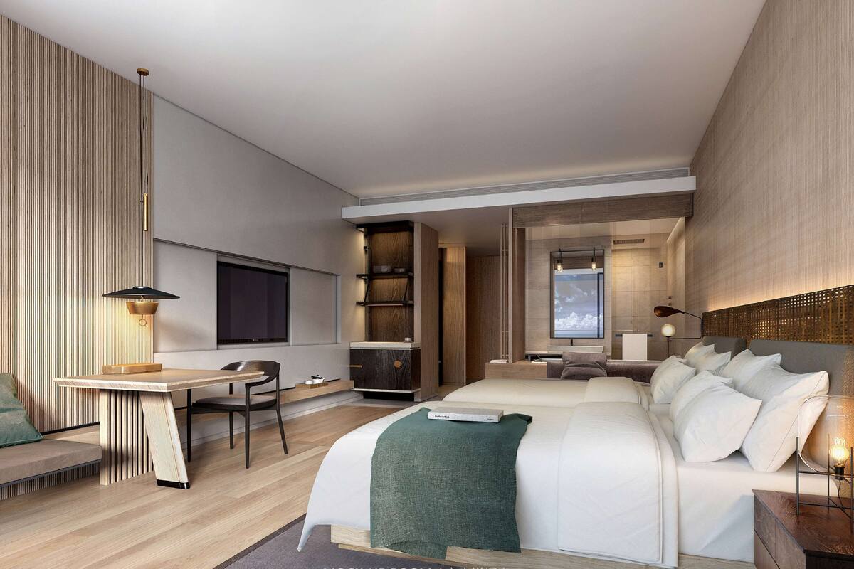 A modern hotel room with a large bed, a desk, and a seating area.