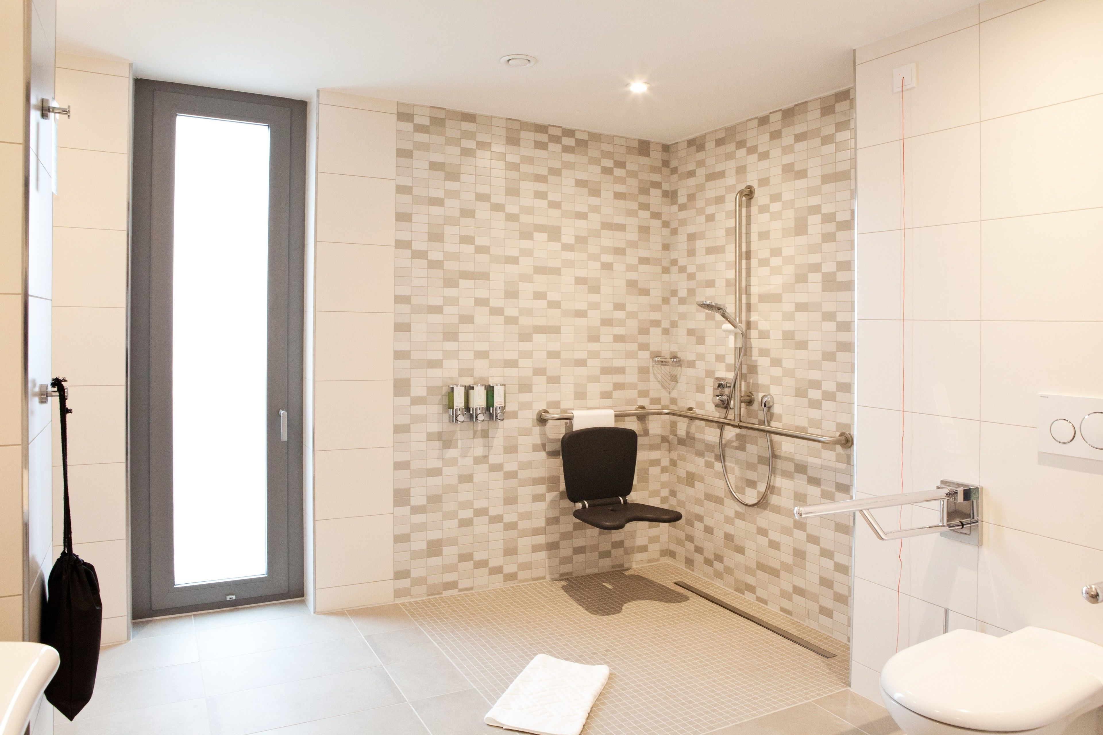 Een moderne badkamer met een douche, toilet en een handdoek op de vloer.