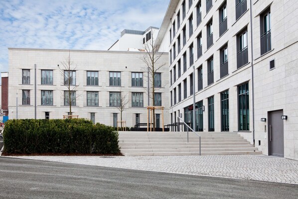 A modern building with a symmetrical facade, large windows, and a central staircase leading to the entrance. - Hampton by Hilton Dortmund Phoenix See (Dortmund)