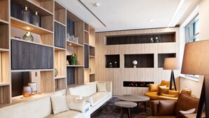 Una sala de estar moderna con un sofá, sillones y una chimenea. También se observan estanterías con objetos decorativos y un televisor de pantalla plana.