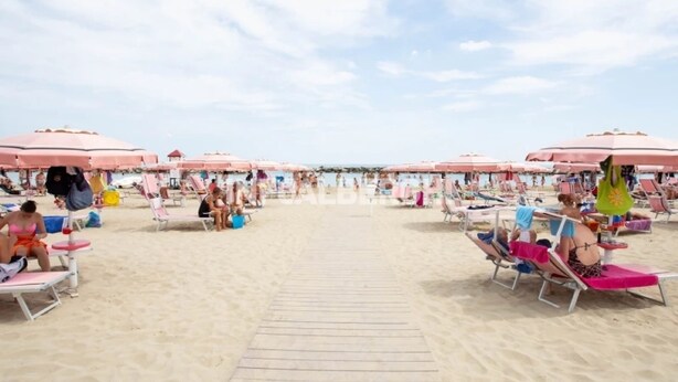 A beach with rows of pink umbrellas and sun loungers. - Hotel Villa Donati (Rimini)