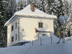 Ein zweistöckiges Gebäude mit verschneitem Dach und Schornstein.