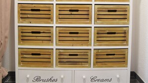 Ein Lagerraum mit Holzkisten, beschriftet mit 'Manolo's Slippers', 'Pinsel' und 'Cremes'.