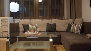Ein modernes Wohnzimmer mit einem Glastisch, einem braunen Sofa und einem weißen Beistelltisch.