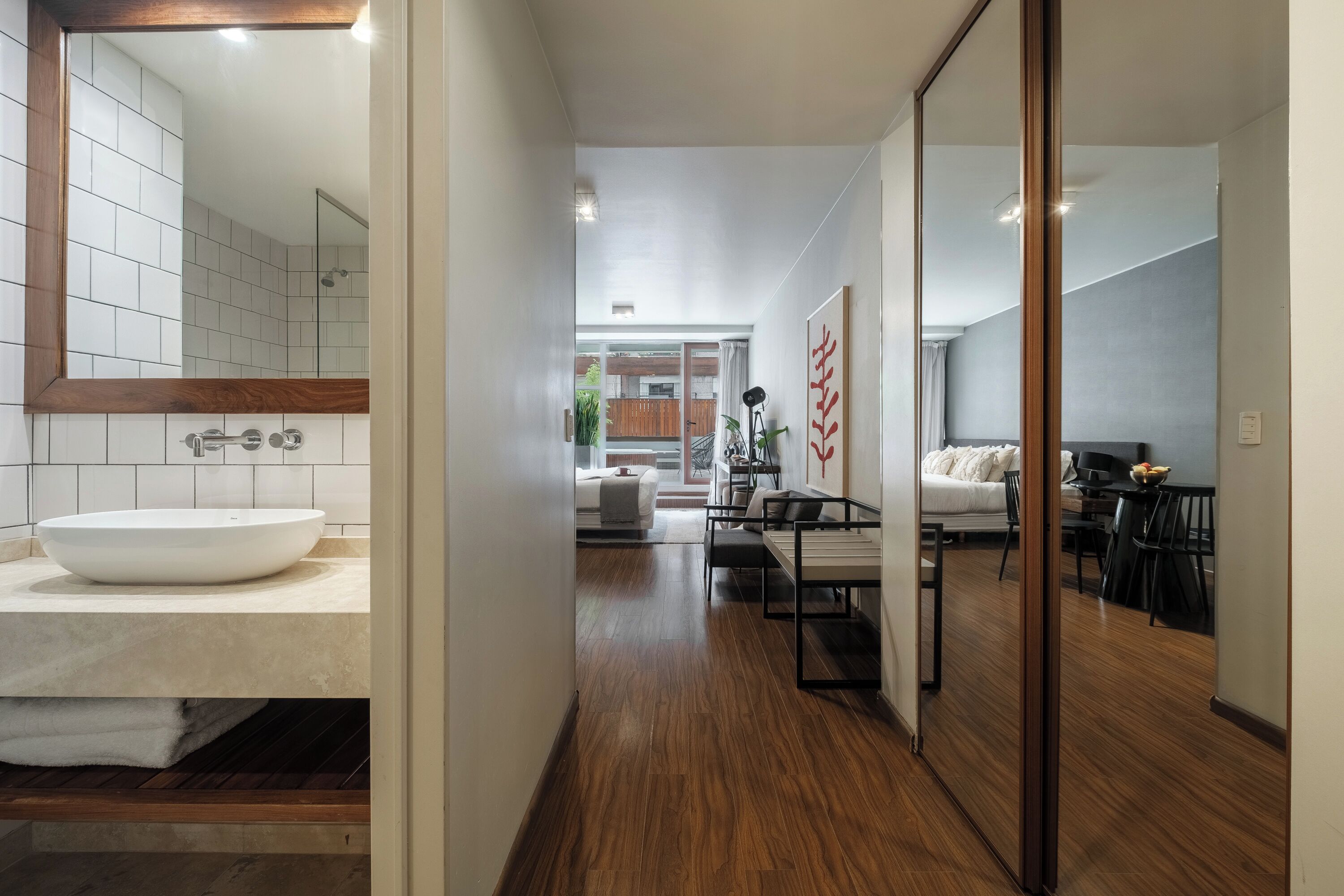 Un baño moderno con un espejo grande, azulejos blancos y un mueble de tocador de madera.