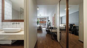 Un baño moderno con un espejo grande, azulejos blancos y un mueble de tocador de madera.