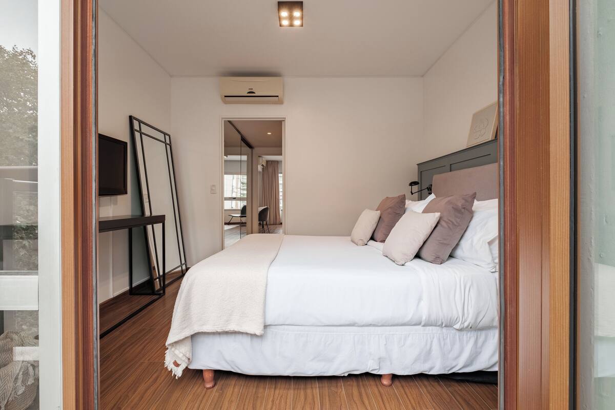 A modern bedroom with a large bed, a TV, and a wooden floor.