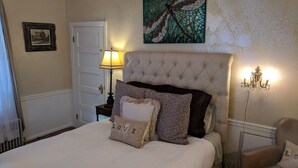 Un lit bien fait, avec une tête de lit capitonnée, une lampe de chevet et des coussins décoratifs.