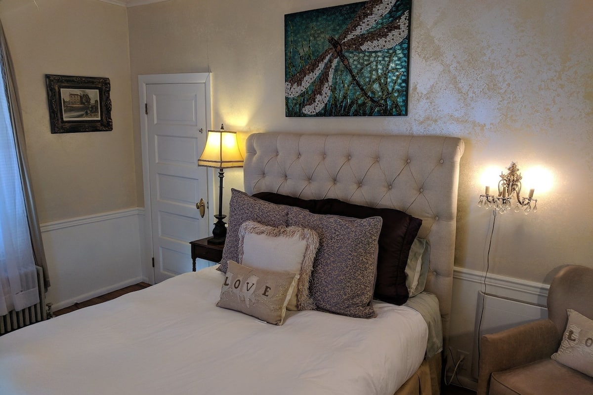 A neatly made bed with a tufted headboard, a bedside lamp, and decorative pillows.