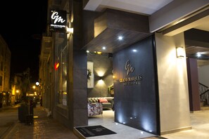 A hotel entrance with a dark facade, a visible reception area, and a staircase to the right. - Grand Marques (San Juan de los Lagos)
