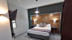 A modern bedroom with a bed, bedside tables, and a TV mounted on the wall.