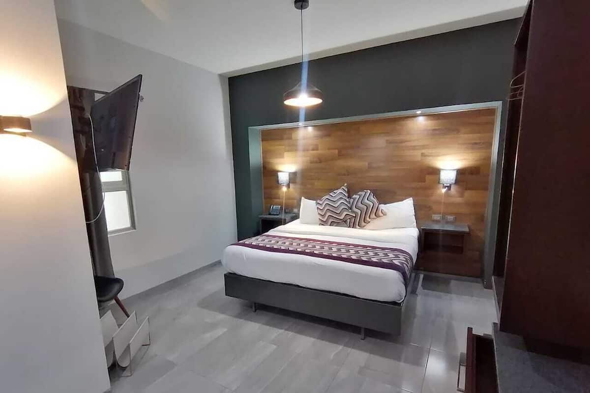 Un dormitorio moderno con una cama, mesitas de noche y un televisor montado en la pared.