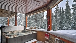 A hot tub under a wooden roof with a view of snow-covered trees. - Chalet Elevation (Breckenridge)