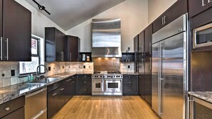 A modern kitchen with dark cabinetry, stainless steel appliances, and a wooden floor. - Chalet Elevation (Breckenridge)