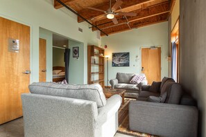A living room with two grey sofas, a wooden ceiling, and a bookshelf. - The Crash Pad - An Uncommon Hostel (Chattanooga)