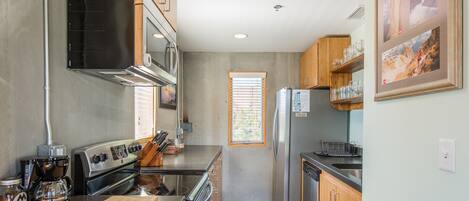 Una cocina moderna con electrodomésticos de acero inoxidable, armarios de madera y un ventanal que proporciona luz natural.